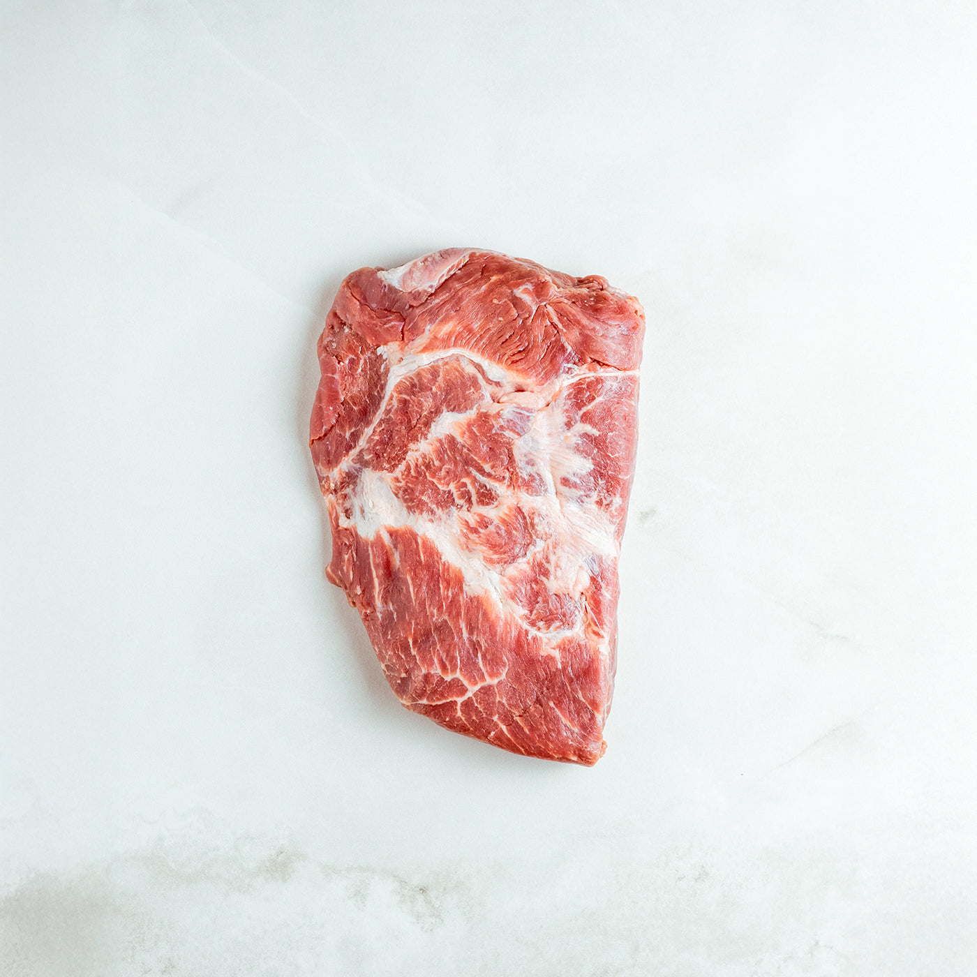 Raw piece of flank steak on a white marble surface