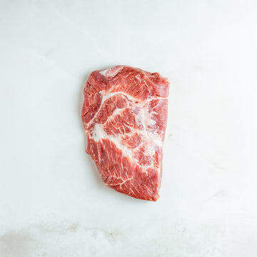 Raw piece of flank steak on a white marble surface