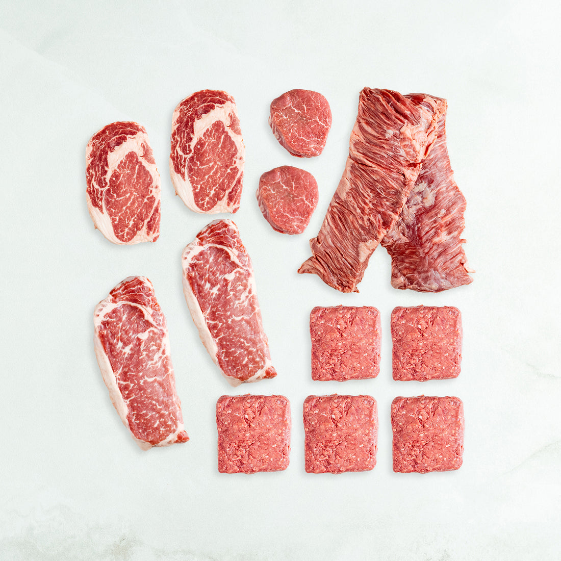 Assorted raw red meats on a light gray background