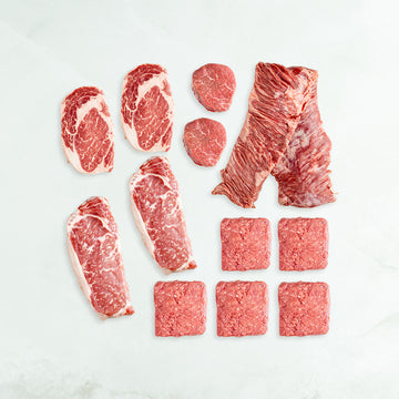 Assorted raw red meats on a light gray background