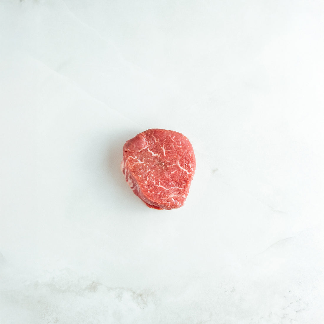 Raw filet steak on a white marble surface