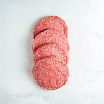 Stack of ground beef patties on a white marble surface