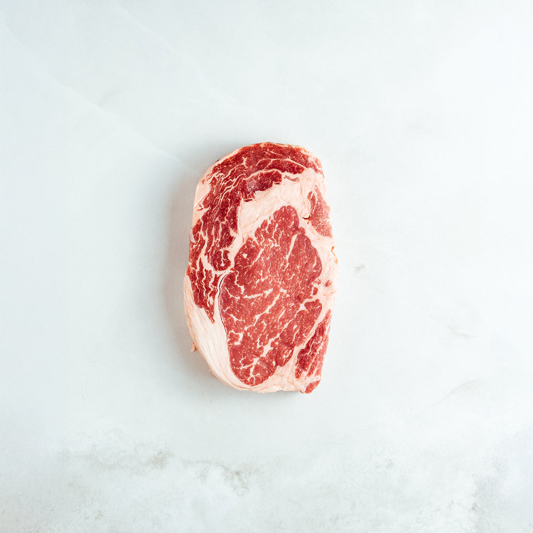 Raw ribeyesteak on a light gray background