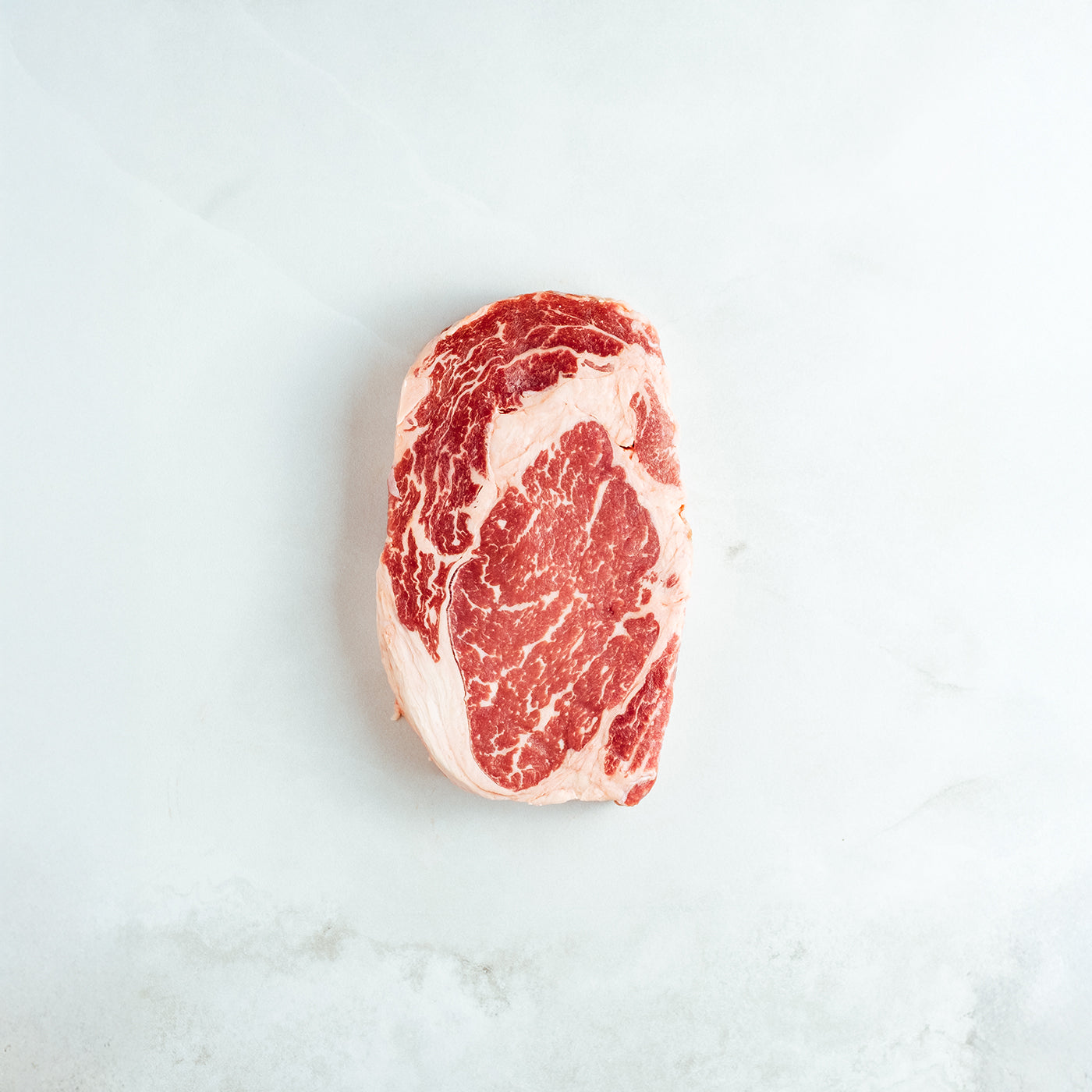 Raw ribeyesteak on a light gray background