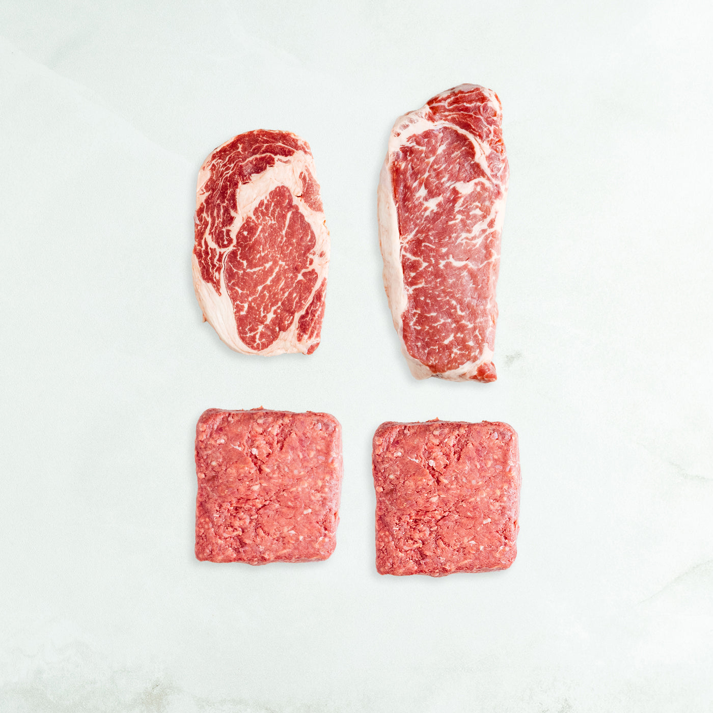 Four pieces of raw meat on a white background