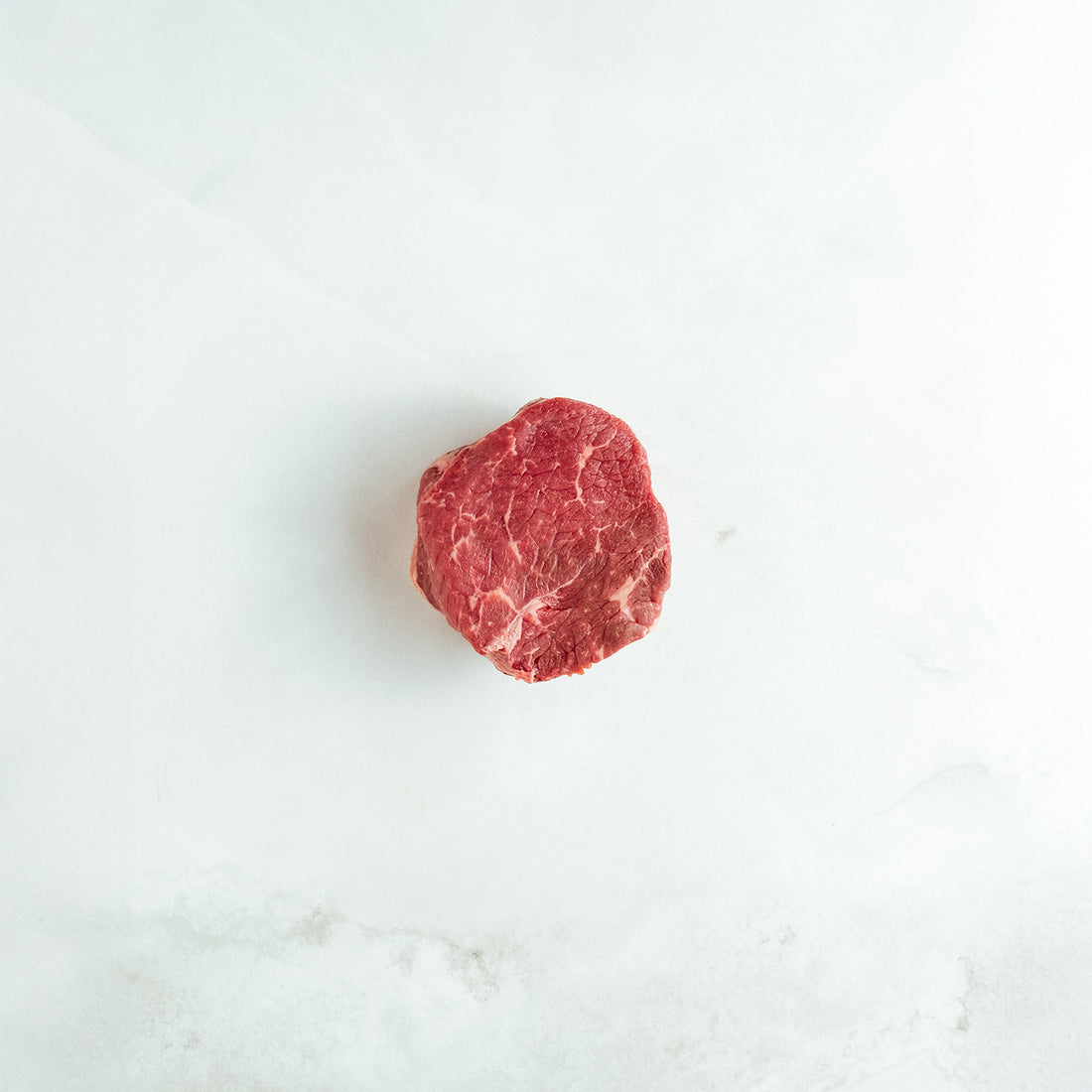 Raw sirloin steak on a white marble surface